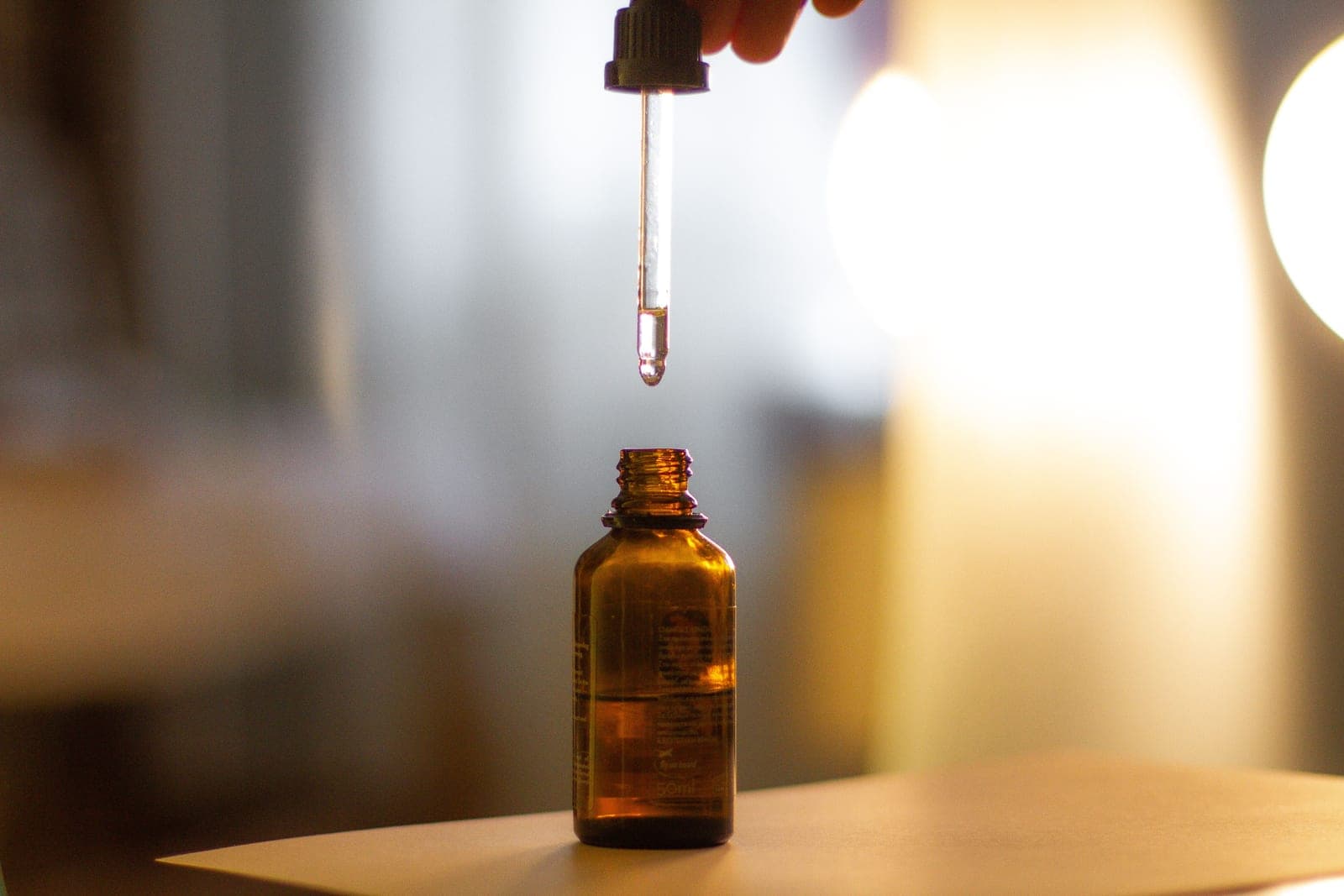 A dropper of skincare serum held in natural daylight